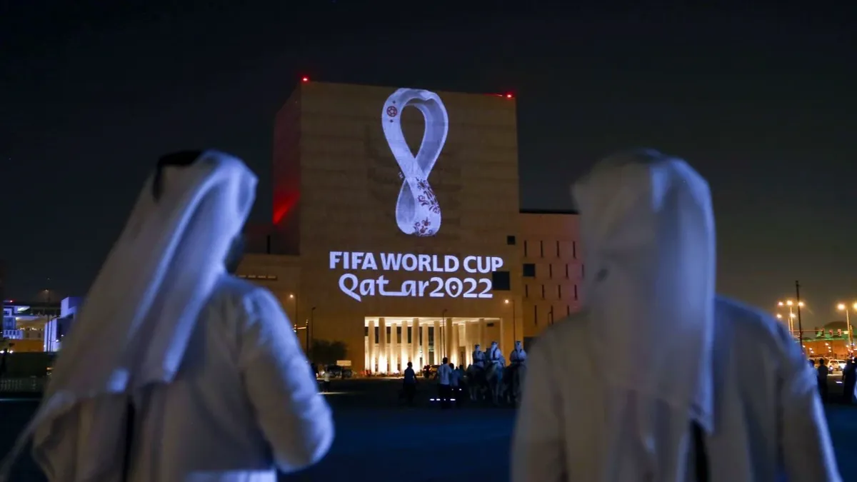 Катарцы собираются на традиционном рынке Сук Вакиф в Дохе, поскольку официальный логотип чемпионата мира по футболу 2022 года проецируется на здание в сентябре 2019 года. Фото: AFP/ Getty Images