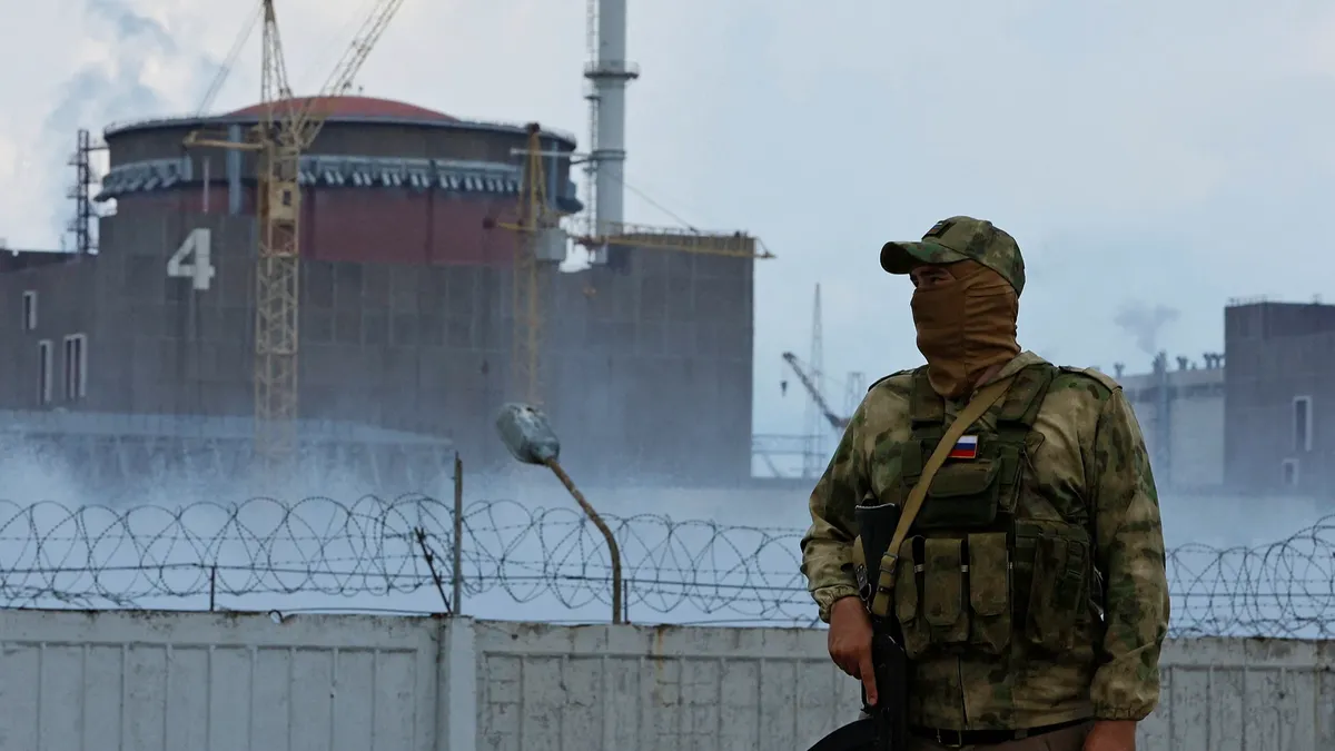 Военнослужащий с российским флагом на форме стоит на страже возле Запорожской атомной электростанции 4 августа. Фото: Александр Ермоченко/Reuters